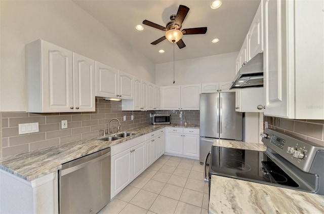 kitchen featuring wall chimney exhaust hood, sink, light stone counters, appliances with stainless steel finishes, and white cabinets