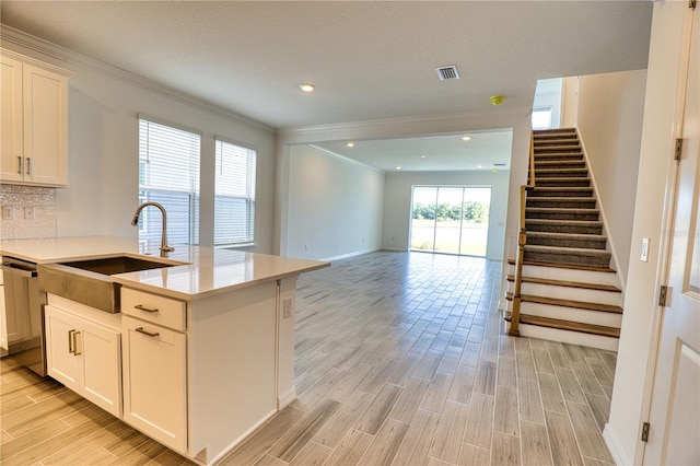 kitchen with sink, a center island with sink, dishwasher, decorative backsplash, and white cabinets