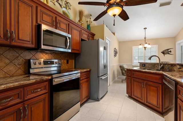 kitchen with sink, stainless steel appliances, hanging light fixtures, light stone countertops, and tasteful backsplash