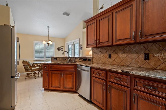 kitchen with appliances with stainless steel finishes, sink, pendant lighting, and light stone counters