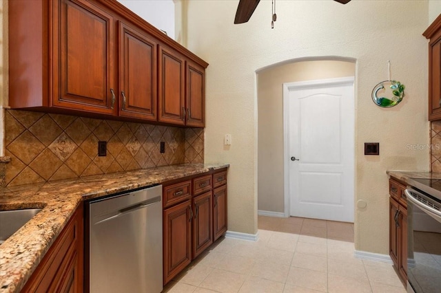 kitchen featuring ceiling fan, light stone counters, appliances with stainless steel finishes, light tile patterned floors, and decorative backsplash