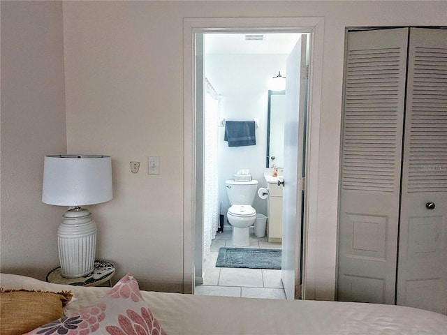 tiled bedroom featuring a closet and ensuite bathroom