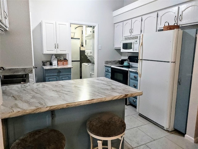 kitchen with stacked washer / dryer, white cabinetry, sink, a kitchen bar, and white appliances