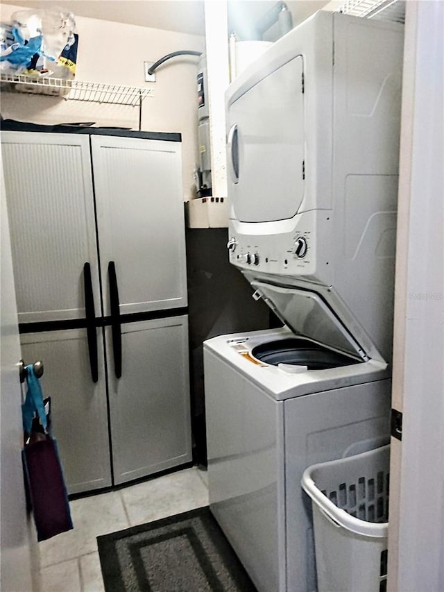 laundry room with light tile patterned flooring and stacked washer / dryer