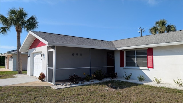 single story home with an attached garage, driveway, a front lawn, and roof with shingles