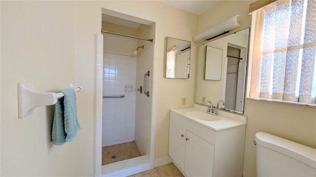 bathroom featuring vanity, toilet, and a tile shower