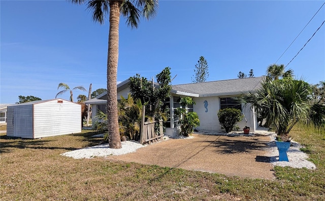 view of front facade featuring a storage shed and a front lawn