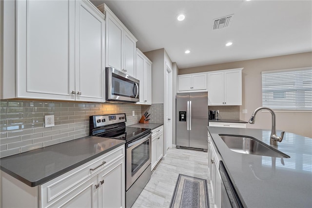 kitchen featuring white cabinetry, sink, backsplash, and appliances with stainless steel finishes