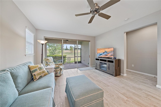 living room featuring ceiling fan, a fireplace, and light hardwood / wood-style floors