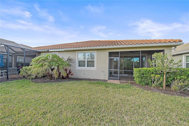 back of house with a lanai and a lawn