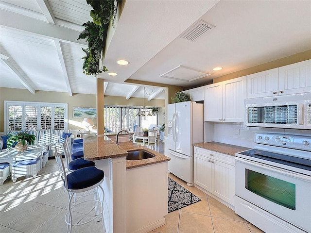 kitchen featuring a kitchen bar, sink, white cabinetry, beamed ceiling, and white appliances