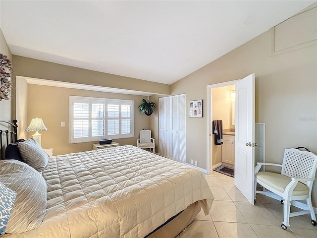 tiled bedroom featuring ensuite bath and lofted ceiling