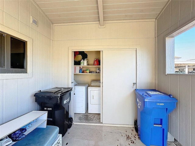 washroom featuring wooden walls and independent washer and dryer