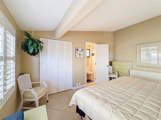 bedroom with light tile patterned flooring, vaulted ceiling, and ensuite bathroom