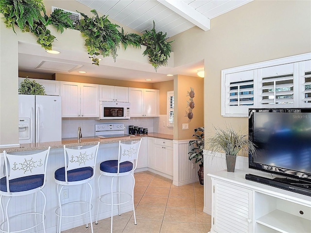 kitchen featuring white cabinetry, light tile patterned floors, backsplash, and white appliances