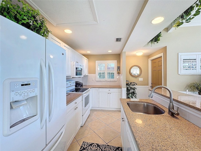 kitchen with sink, white cabinets, light tile patterned floors, light stone countertops, and white appliances