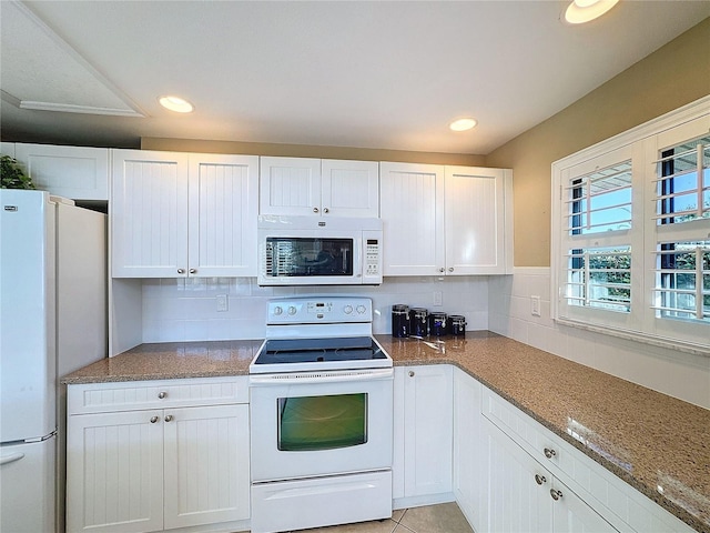 kitchen featuring tasteful backsplash, white cabinets, white appliances, and dark stone counters