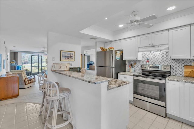 kitchen with tasteful backsplash, white cabinets, light stone counters, ceiling fan, and stainless steel appliances