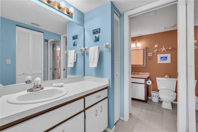 bathroom with vanity, tile patterned flooring, toilet, and a textured ceiling