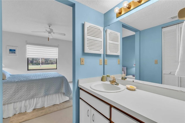 bathroom with ceiling fan, vanity, and a textured ceiling