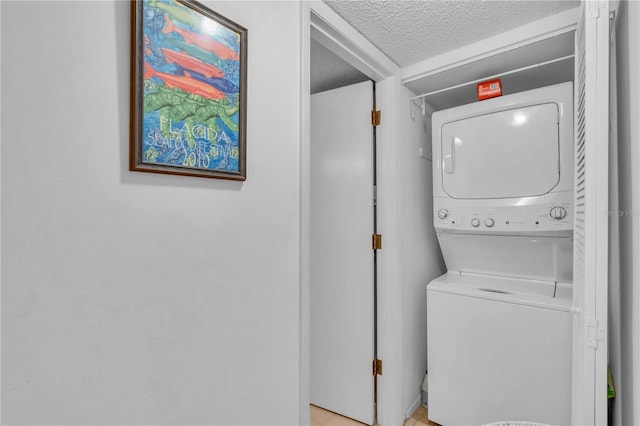 clothes washing area featuring stacked washer and dryer and a textured ceiling