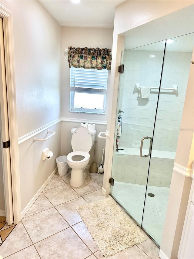 bathroom featuring tile patterned floors, toilet, and a shower with shower door