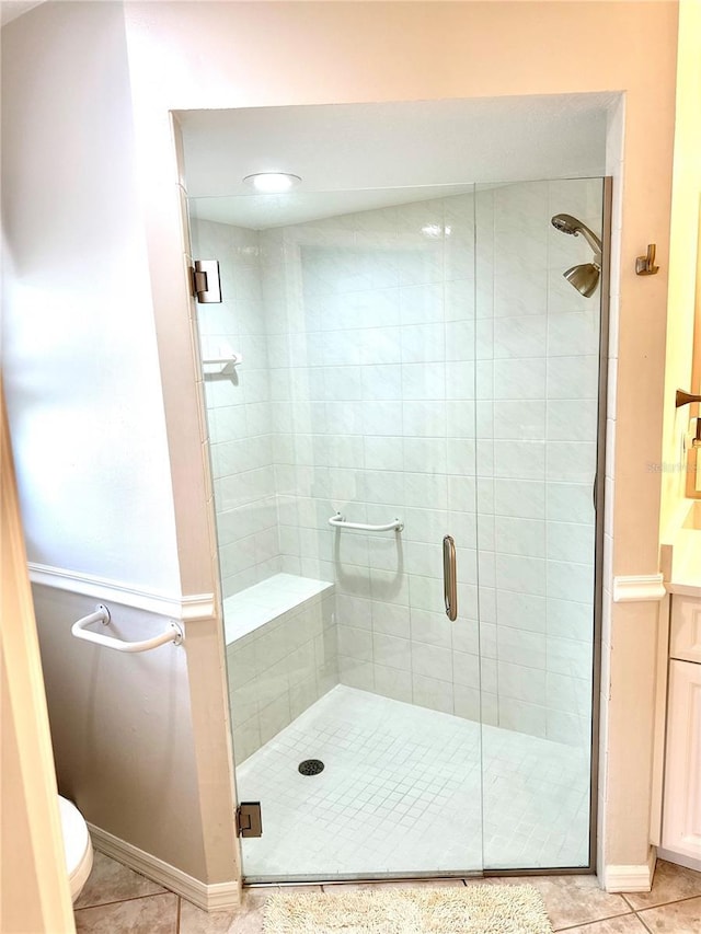 bathroom featuring tile patterned flooring, a shower with door, and toilet