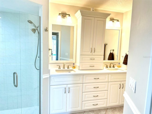 bathroom featuring a shower with door, vanity, tile patterned floors, and a textured ceiling