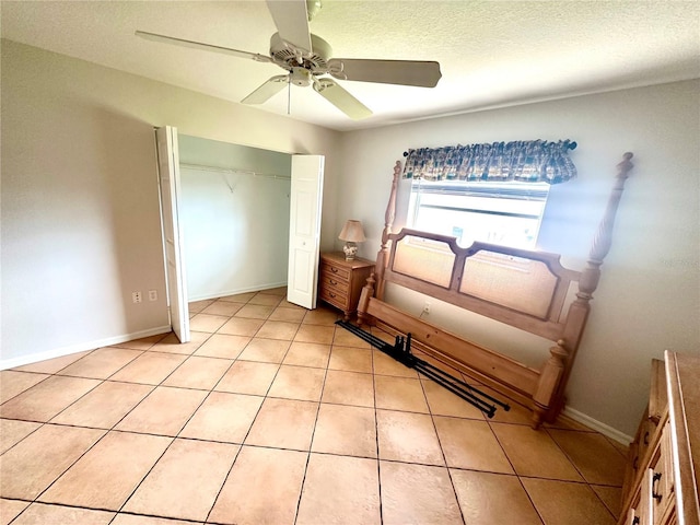 unfurnished bedroom with a textured ceiling, a closet, ceiling fan, and light tile patterned flooring