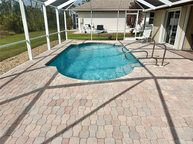 view of pool featuring a yard, glass enclosure, and a patio area