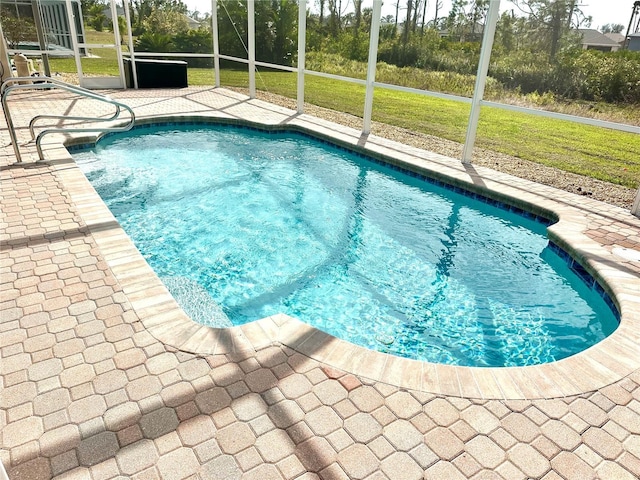 view of pool featuring a yard, glass enclosure, and a patio area