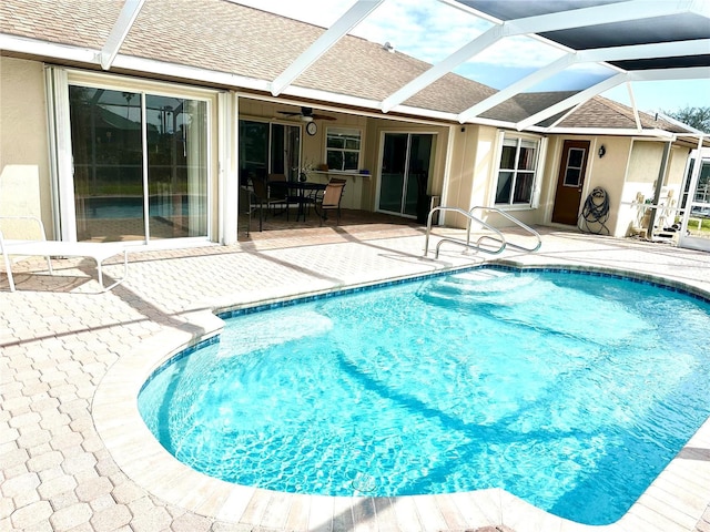 view of pool featuring ceiling fan, glass enclosure, and a patio area