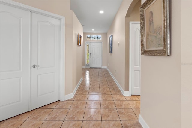 hall with arched walkways, recessed lighting, baseboards, and light tile patterned floors