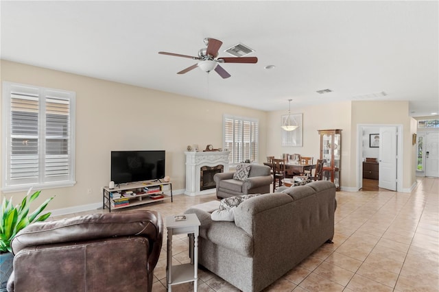 living area featuring a ceiling fan, visible vents, baseboards, and light tile patterned floors