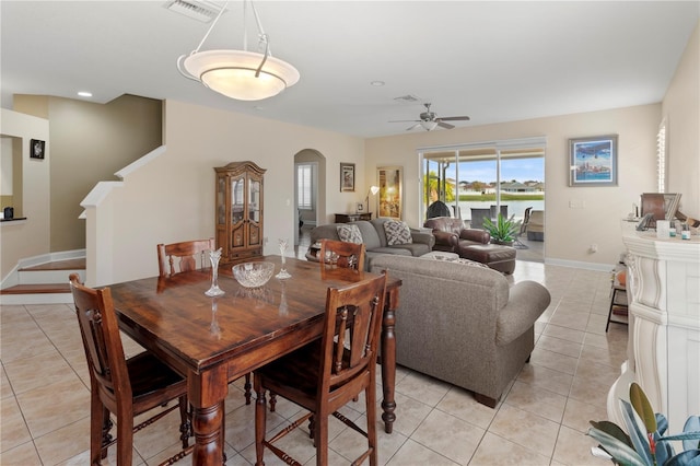 dining area with arched walkways, light tile patterned flooring, visible vents, baseboards, and a ceiling fan