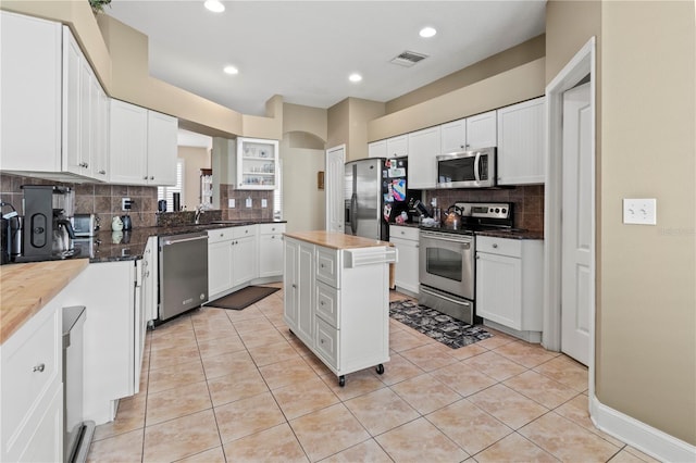 kitchen with visible vents, white cabinets, arched walkways, appliances with stainless steel finishes, and light tile patterned flooring