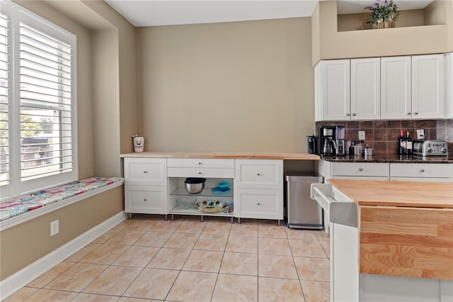 kitchen featuring decorative backsplash, white cabinetry, wooden counters, built in desk, and light tile patterned flooring