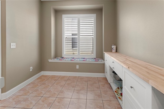 interior space featuring light tile patterned flooring and baseboards