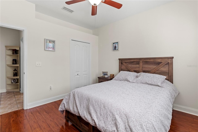 bedroom with wood finished floors, visible vents, and baseboards