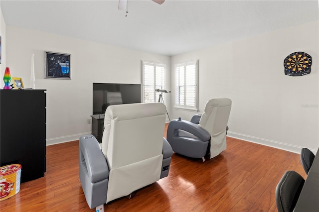 interior space with wood finished floors, a ceiling fan, and baseboards