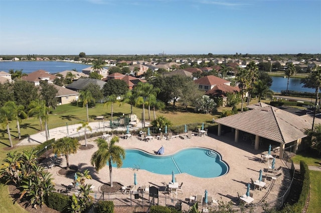 pool featuring a water view, a patio area, a residential view, and fence