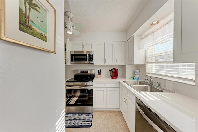 kitchen with sink, white cabinets, ceiling fan, stainless steel appliances, and a textured ceiling