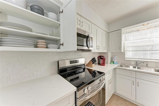 kitchen with stainless steel appliances, tasteful backsplash, sink, and white cabinets