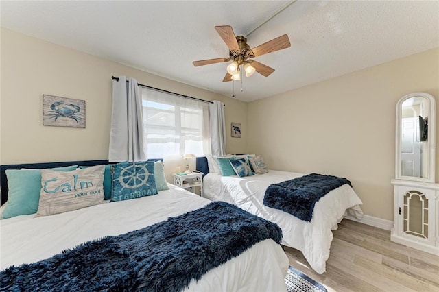 bedroom with ceiling fan, light hardwood / wood-style flooring, and a textured ceiling