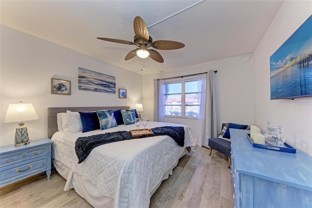 bedroom with ceiling fan, light hardwood / wood-style flooring, and a textured ceiling