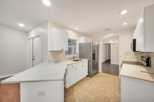 kitchen with appliances with stainless steel finishes, pendant lighting, sink, white cabinets, and kitchen peninsula