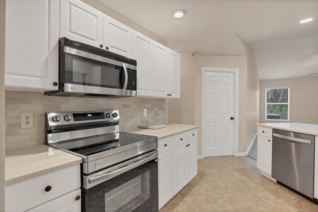 kitchen with tasteful backsplash, light tile patterned floors, stainless steel appliances, and white cabinets