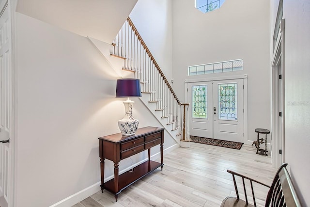 entryway featuring french doors, light hardwood / wood-style flooring, and a high ceiling