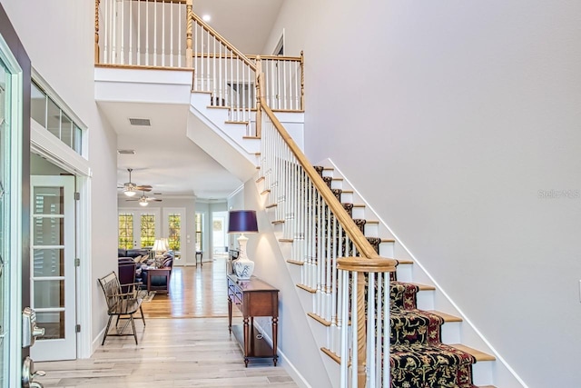 stairs with hardwood / wood-style flooring, ceiling fan, and a high ceiling