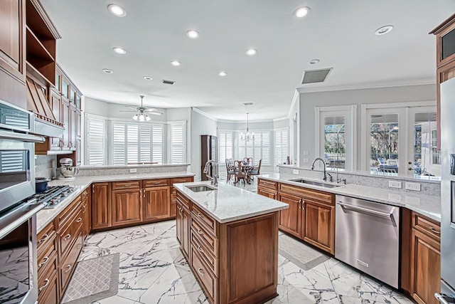 kitchen featuring decorative light fixtures, sink, stainless steel appliances, light stone countertops, and a center island with sink